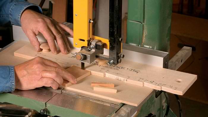 A man using a jig on a band saw